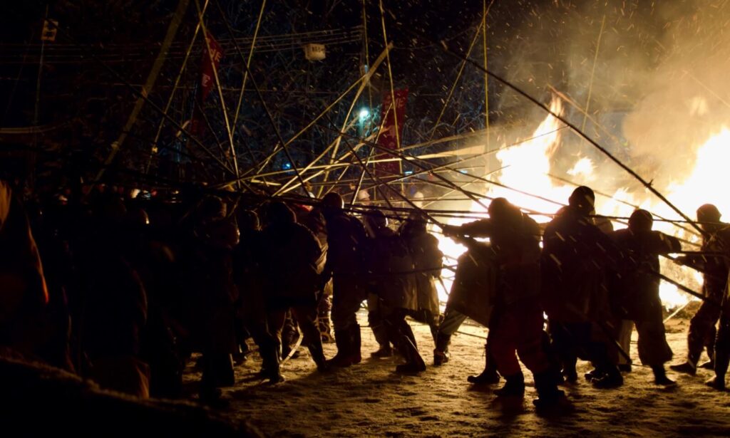 Participants clashing in the takeuchi bamboo battle lit by the sacred fire. 